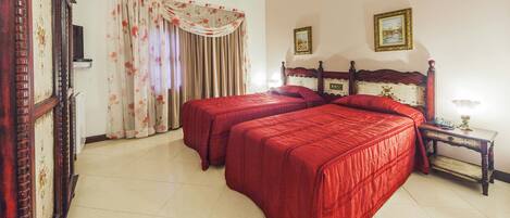 Un dormitorio con dos camas, cabecero de madera, mesita de noche y ventana con cortinas.