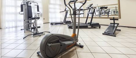 Un gimnasio con diversos equipos de ejercicio, incluyendo cintas de correr y una máquina elíptica.
