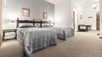 A bedroom with two beds, a nightstand, a dresser, and a small table.