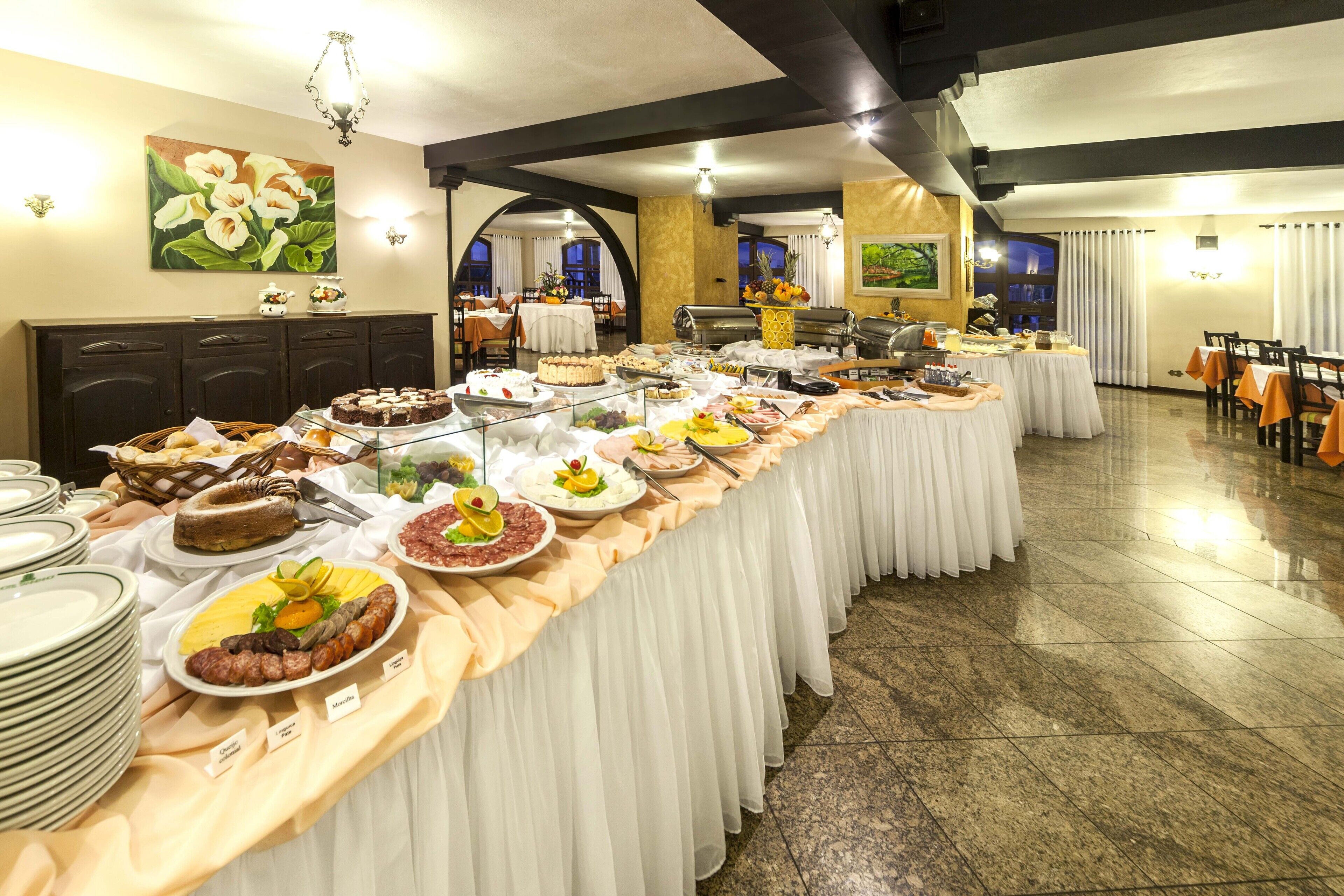 A buffet setup with various food items and a long table covered with a white tablecloth.