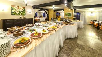 A buffet setup with various food items and a long table covered with a white tablecloth.