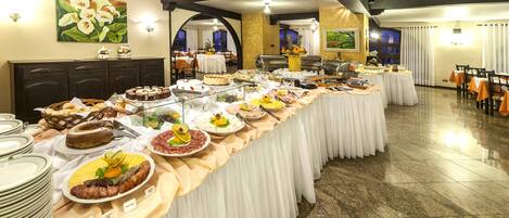 A buffet setup with various food items and a long table covered with a white tablecloth.