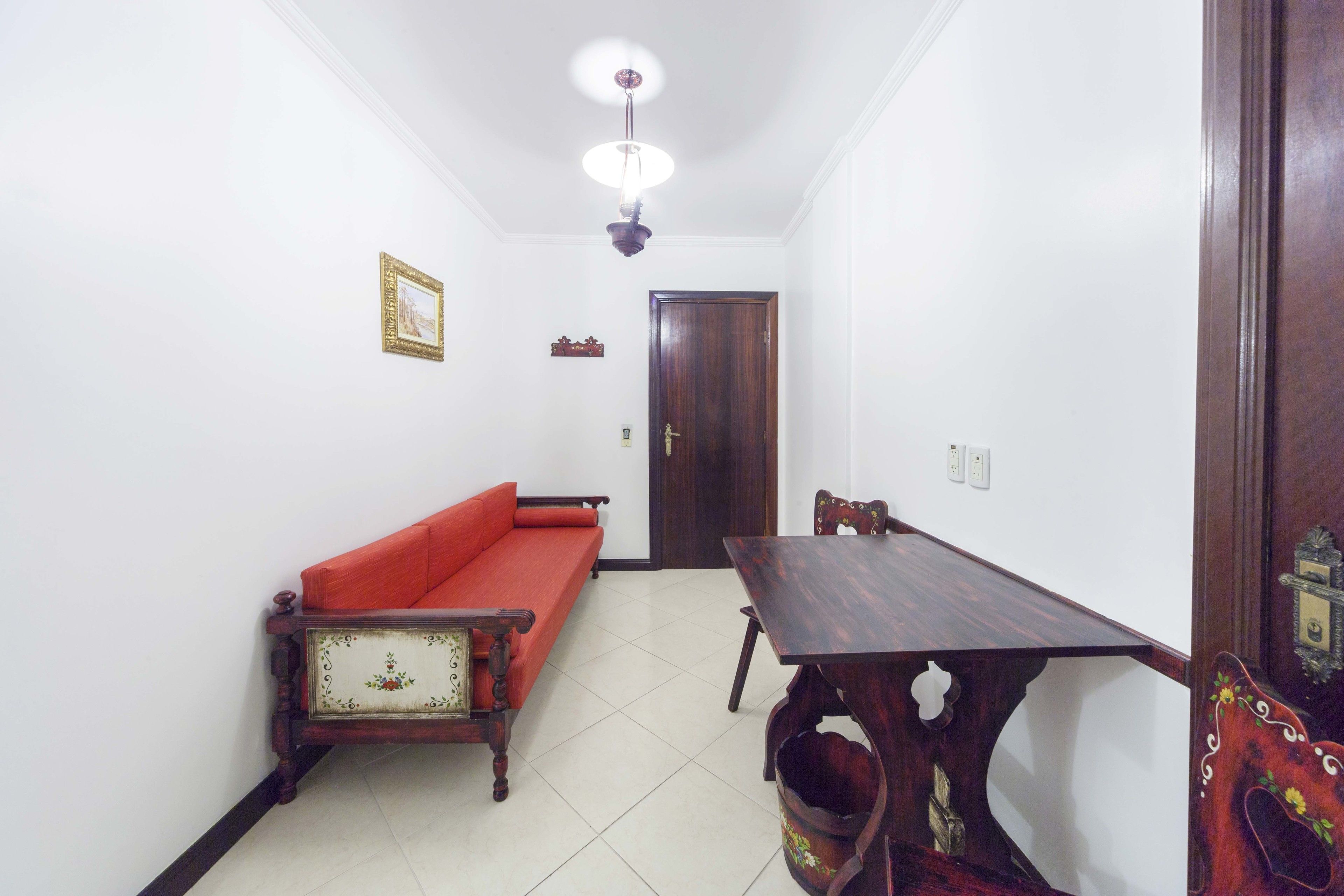 Un comedor con una mesa y sillas de madera, un sofá rojo y una puerta de madera.
