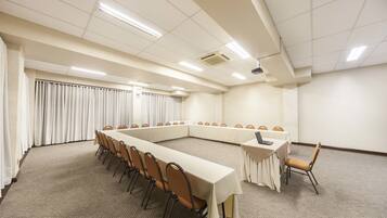Una sala de conferencias con una larga mesa y sillas, una mesa más pequeña con un ordenador portátil y suelo alfombrado.