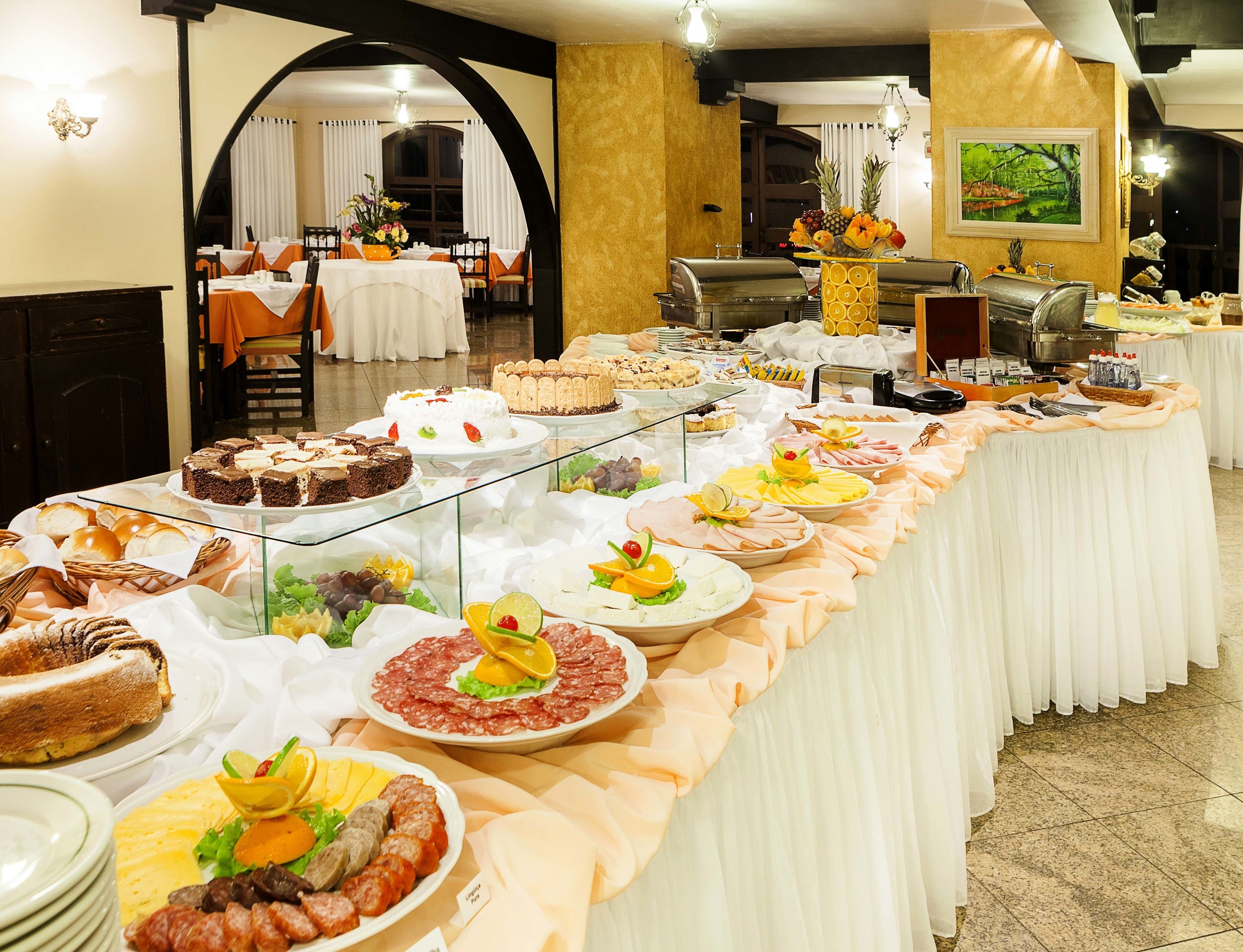 Een buffet met diverse gerechten, waaronder taarten, gebak en een presentatie van fruit.