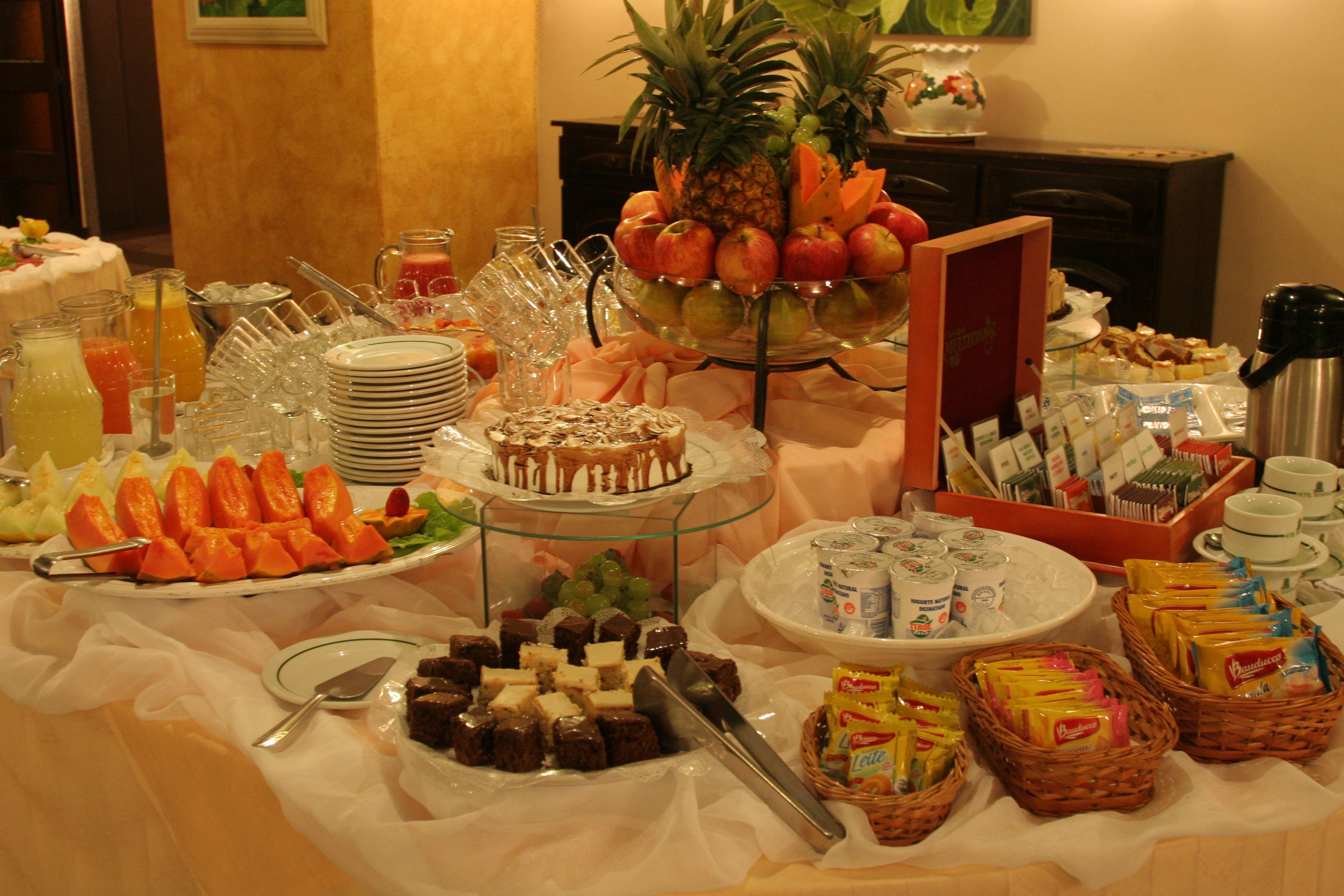 Una mesa de buffet con diversos alimentos, como frutas, postres y bebidas.