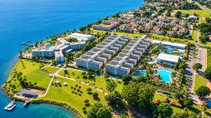 Une vue aérienne d’un complexe hôtelier comprenant plusieurs bâtiments, un port de plaisance et une grande piscine.