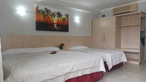 Een hotelkamer met twee bedden, een grote kledingkast en een schilderij van palmbomen aan de muur.