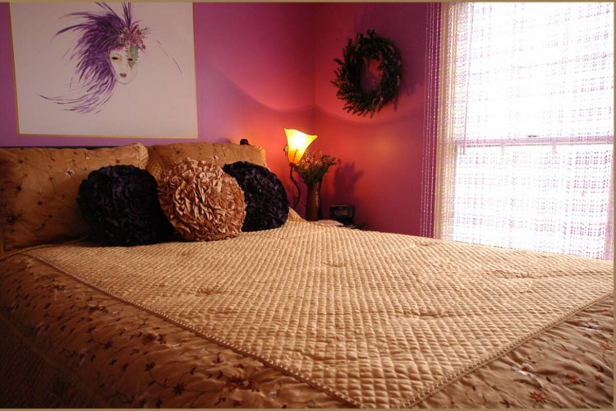 Une chambre à coucher avec un lit, des oreillers, une table de chevet, une lampe et un élément décoratif mural.