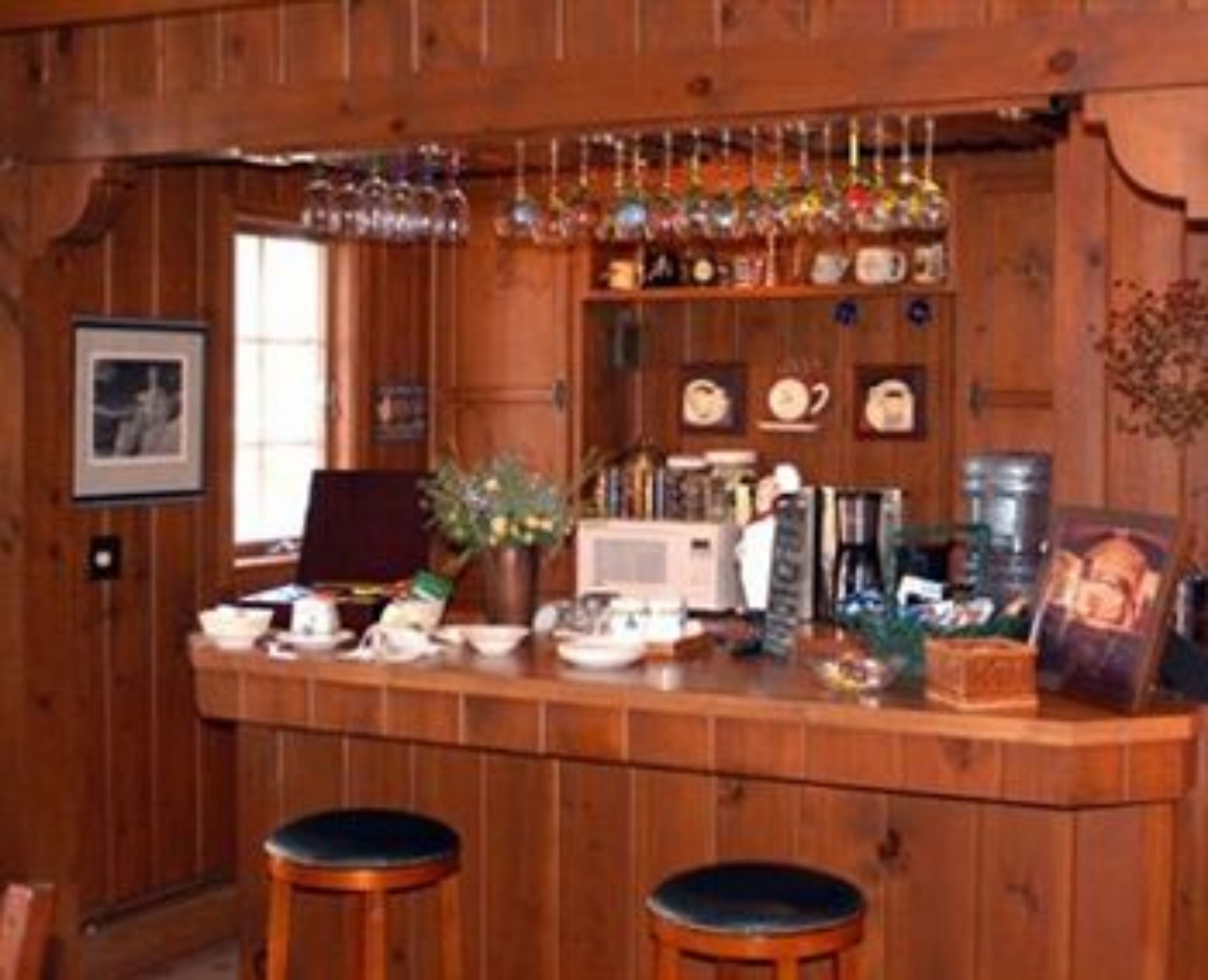 A wooden bar area with stools, a microwave, a coffee maker, and various kitchen items.