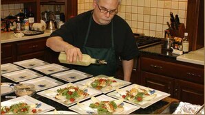 A chef preparing food in a kitchen with multiple plates of dishes on the counter.