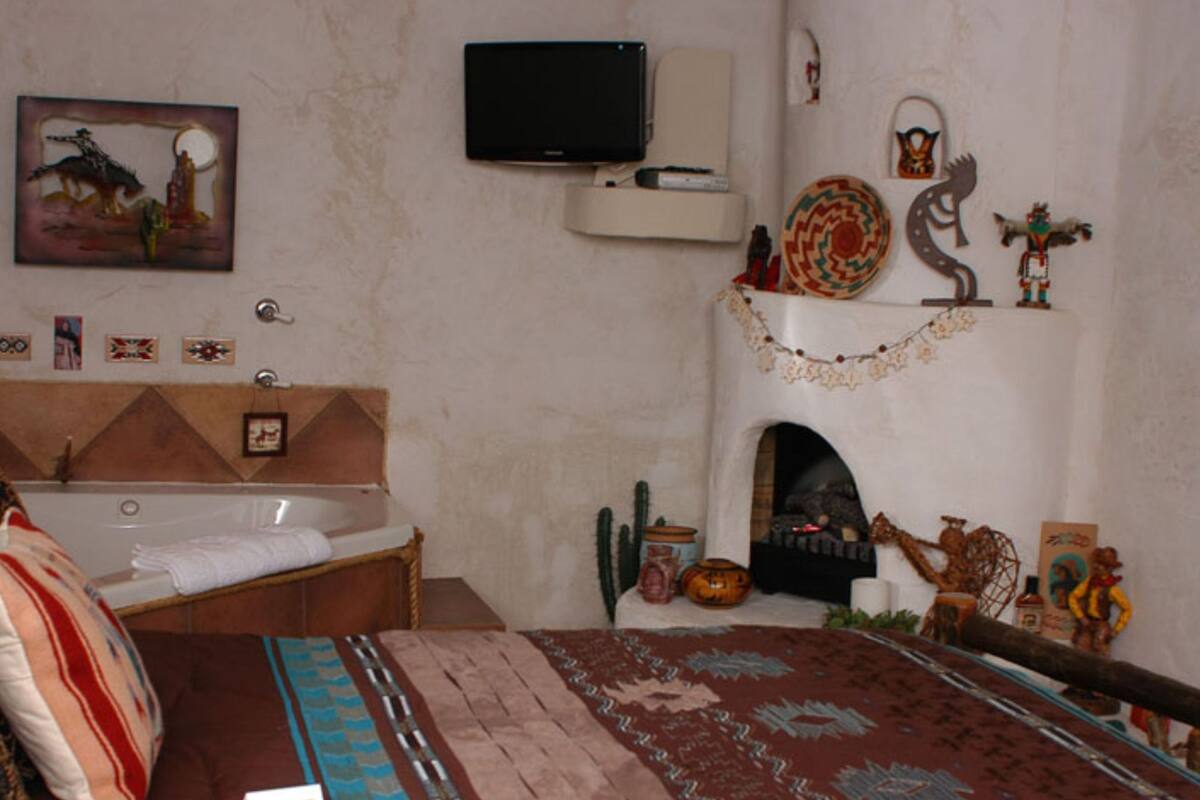 Une chambre à coucher avec un lit, une baignoire, une télévision et une cheminée.