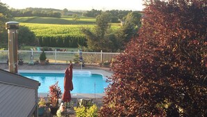 A swimming pool with a white fence, surrounded by potted plants and outdoor furniture.