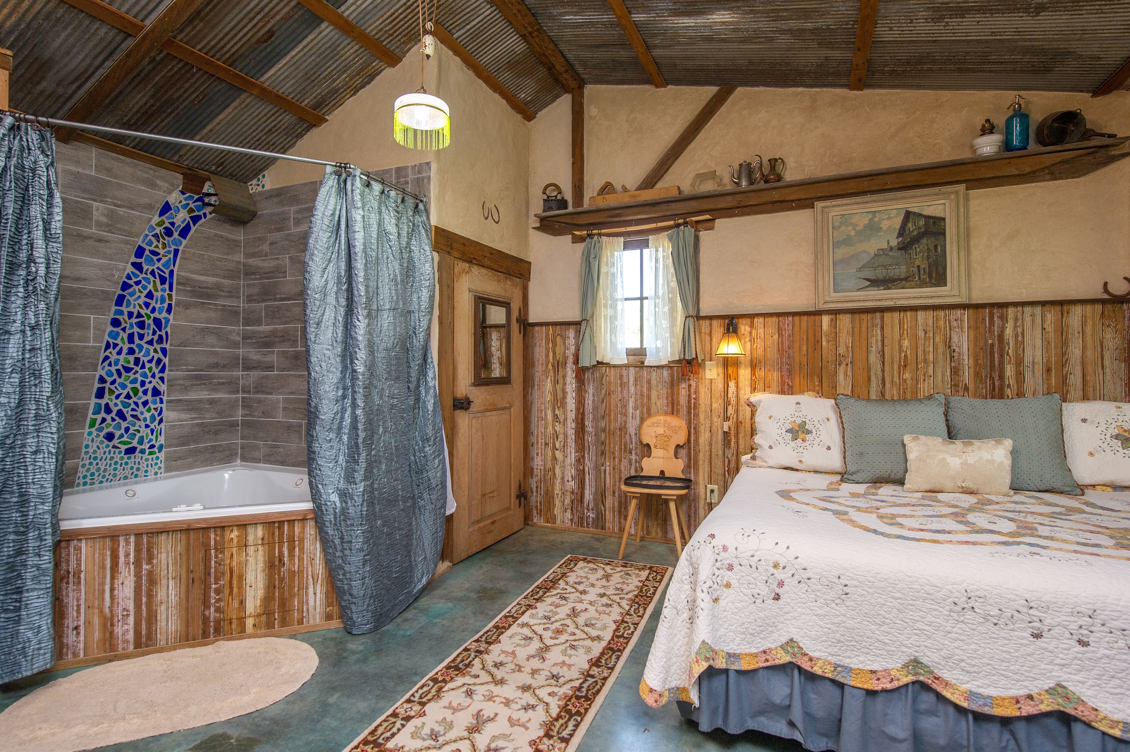 A rustic bathroom with a bathtub, shower, and wooden walls.