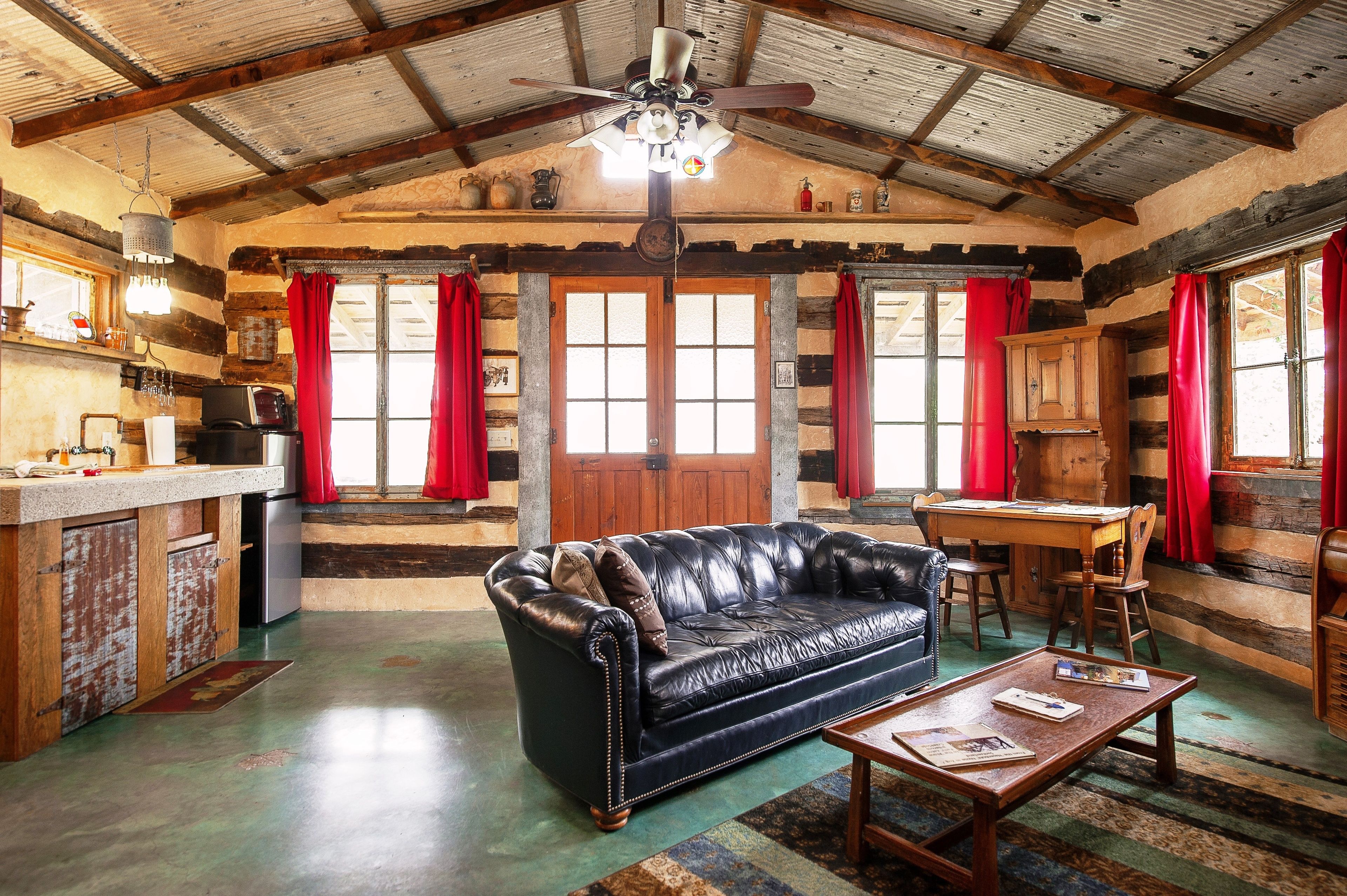 Ein rustikales Blockhaus-Interieur mit Ledersofa, Holztisch und Küchenzeile.