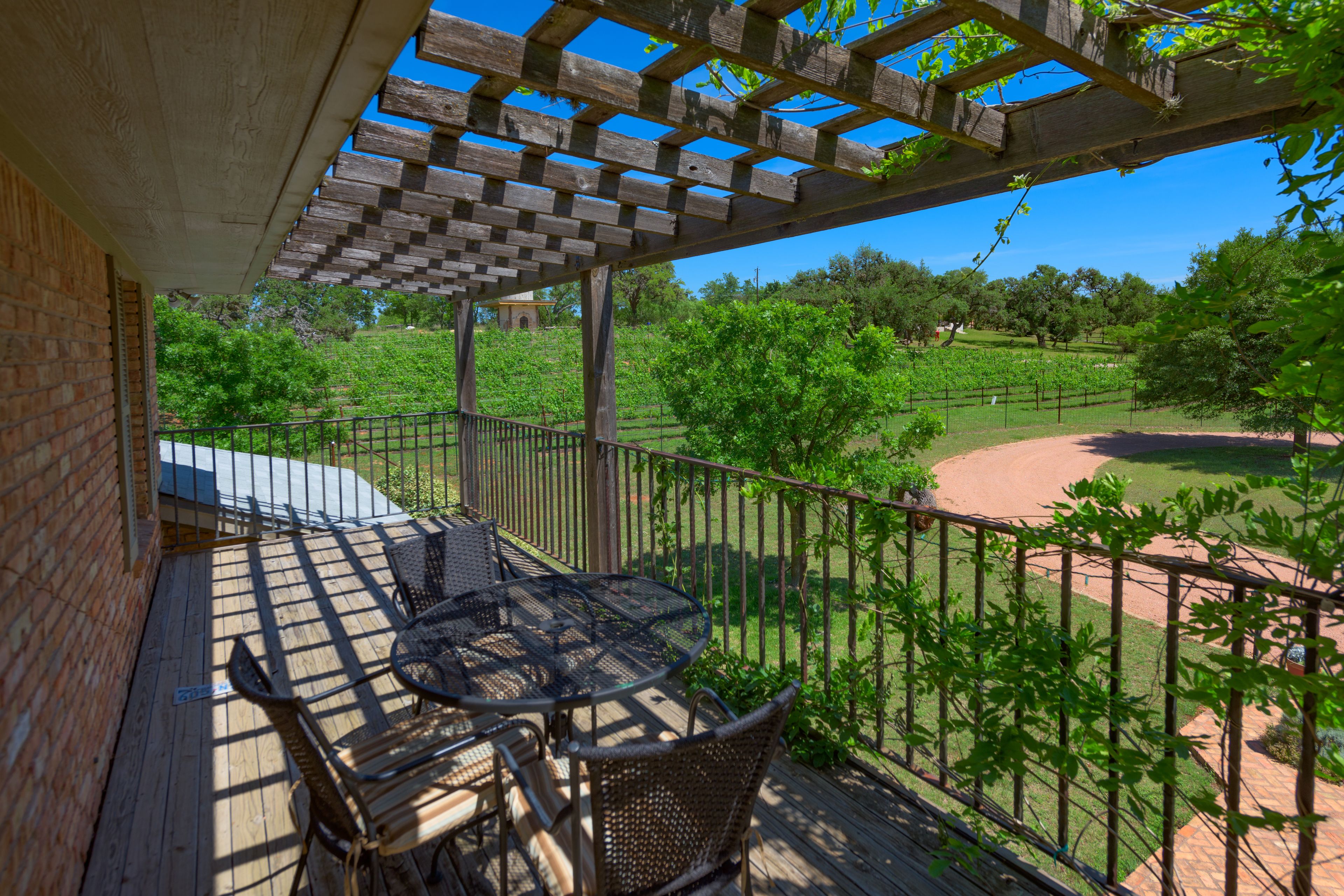 Une terrasse en bois agrémentée d’une pergola, d’un espace salon extérieur et offrant une vue sur un vignoble.