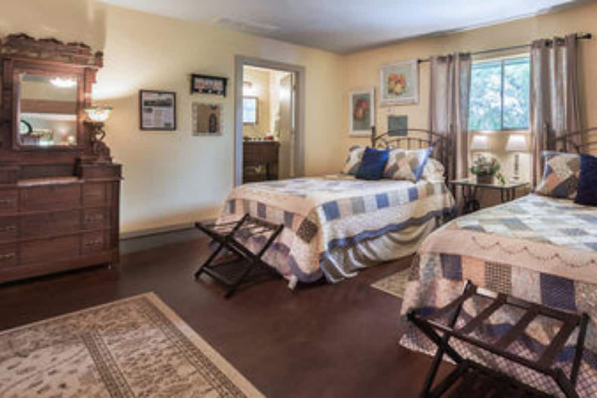 Un dormitorio con dos camas, un tocador, un espejo y una ventana con cortinas.
