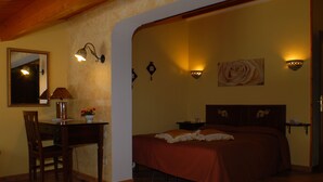 A bedroom with a bed, a desk, a chair, a mirror, and wall-mounted lights. - B&B Triskeles (Syracuse)