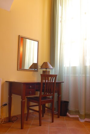 A wooden desk with a lamp, a chair, a mirror, and a window with curtains. - B&B Triskeles (Syracuse)
