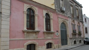 A pink building with arched windows and a green door. - B&B Triskeles (Syracuse)