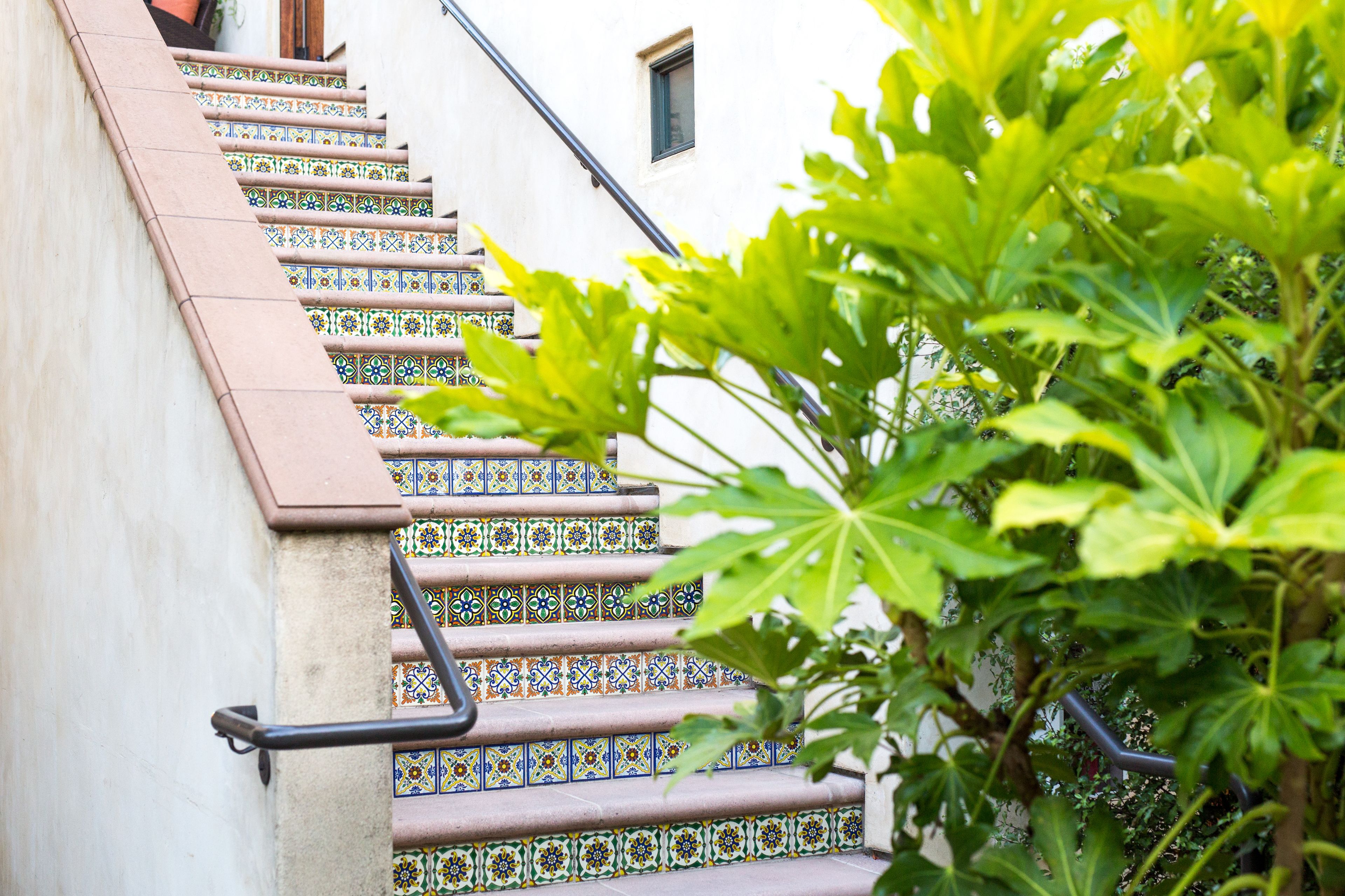 A staircase with colorful patterned tiles and a metal handrail.