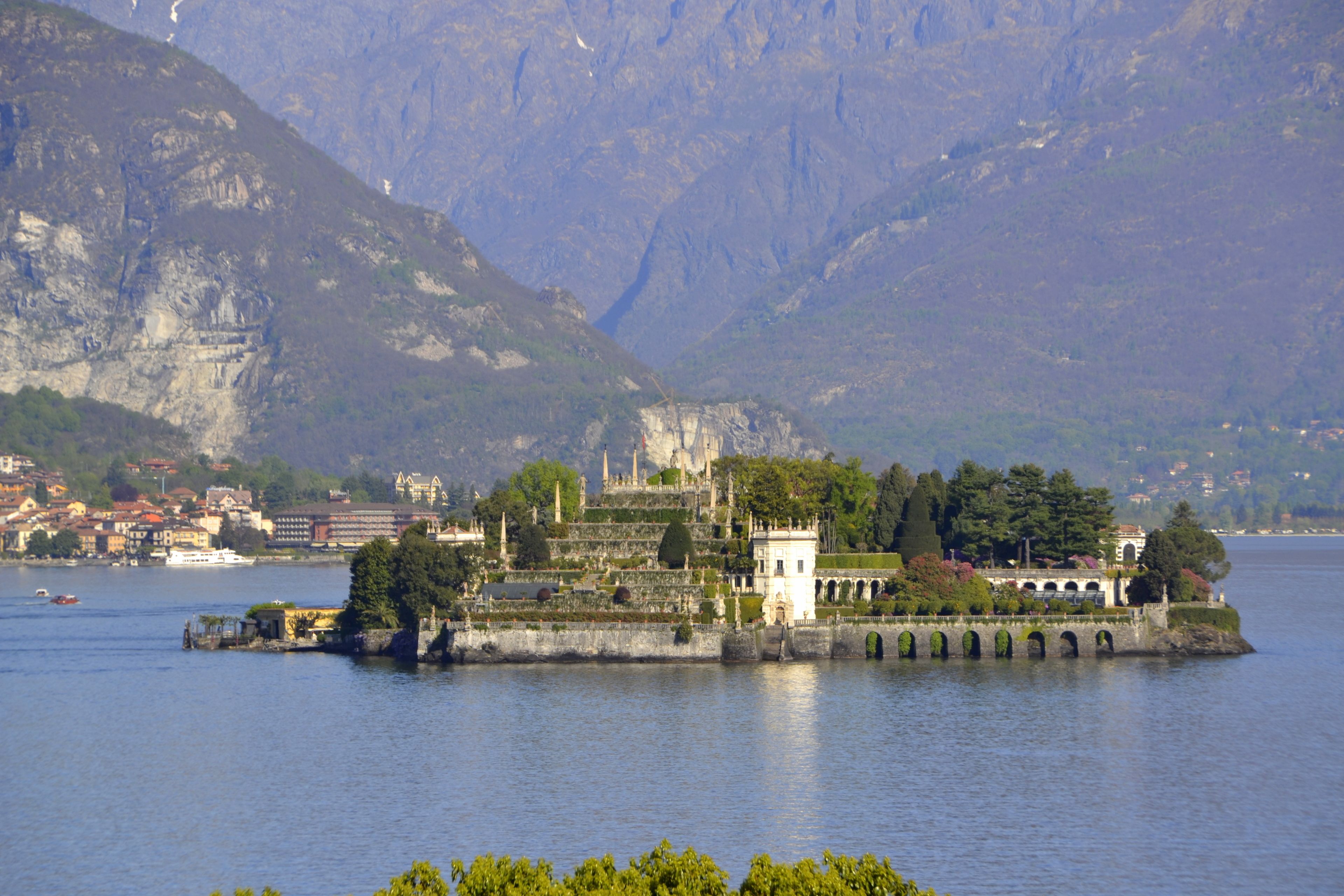 A historic castle on a lake surrounded by mountains.