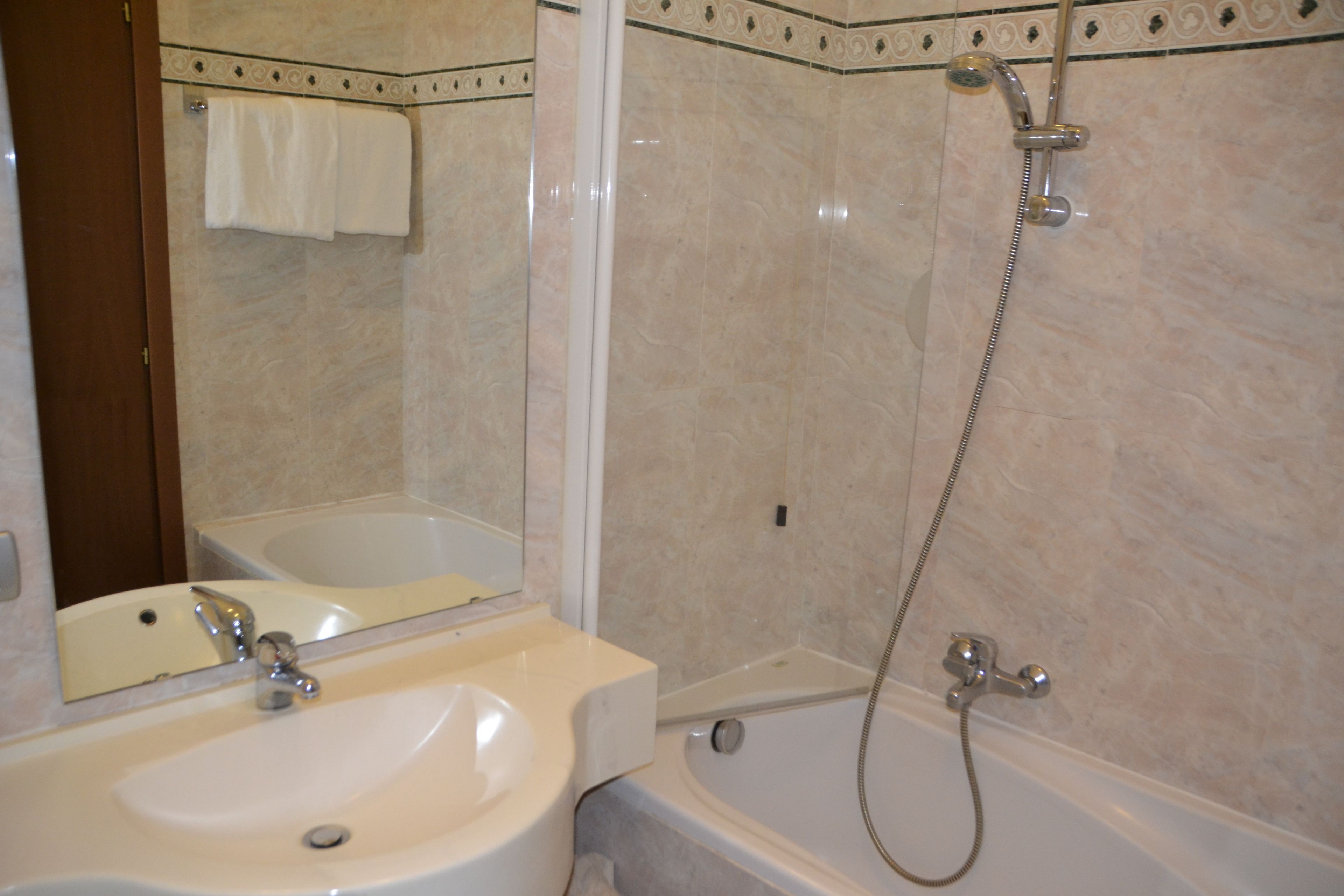 Un baño con lavamanos, espejo, bañera y ducha.