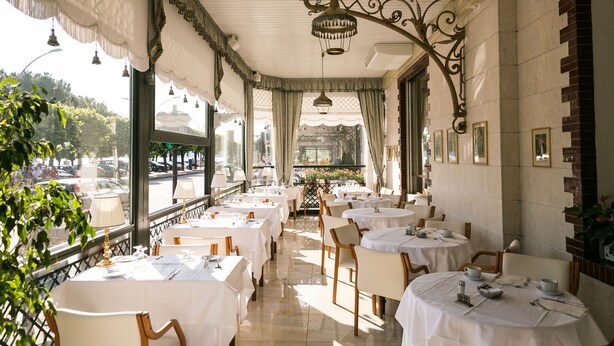 A restaurant with round tables, white tablecloths, and hanging lamps. - Hotel Milan Speranza Au Lac (Stresa)