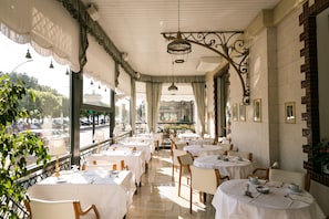 A restaurant with round tables, white tablecloths, and hanging lamps. - Hotel Milan Speranza Au Lac (Stresa)