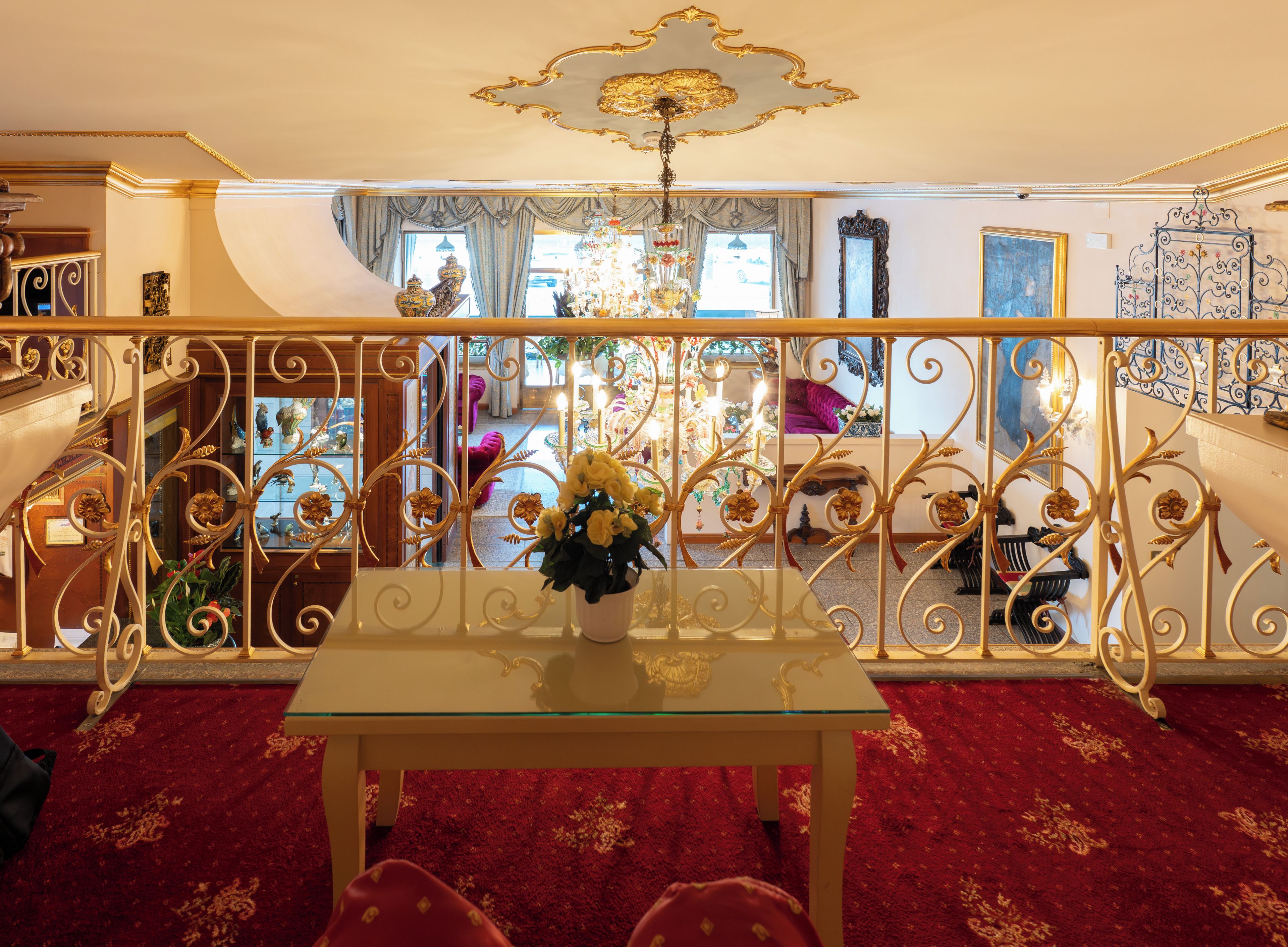 Una sala espaciosa con una mesa de vidrio, barandilla ornamentada y un candelabro.