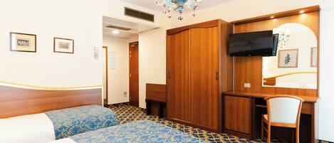 Una habitación de hotel con una cama, un escritorio, una silla, un televisor y una araña.