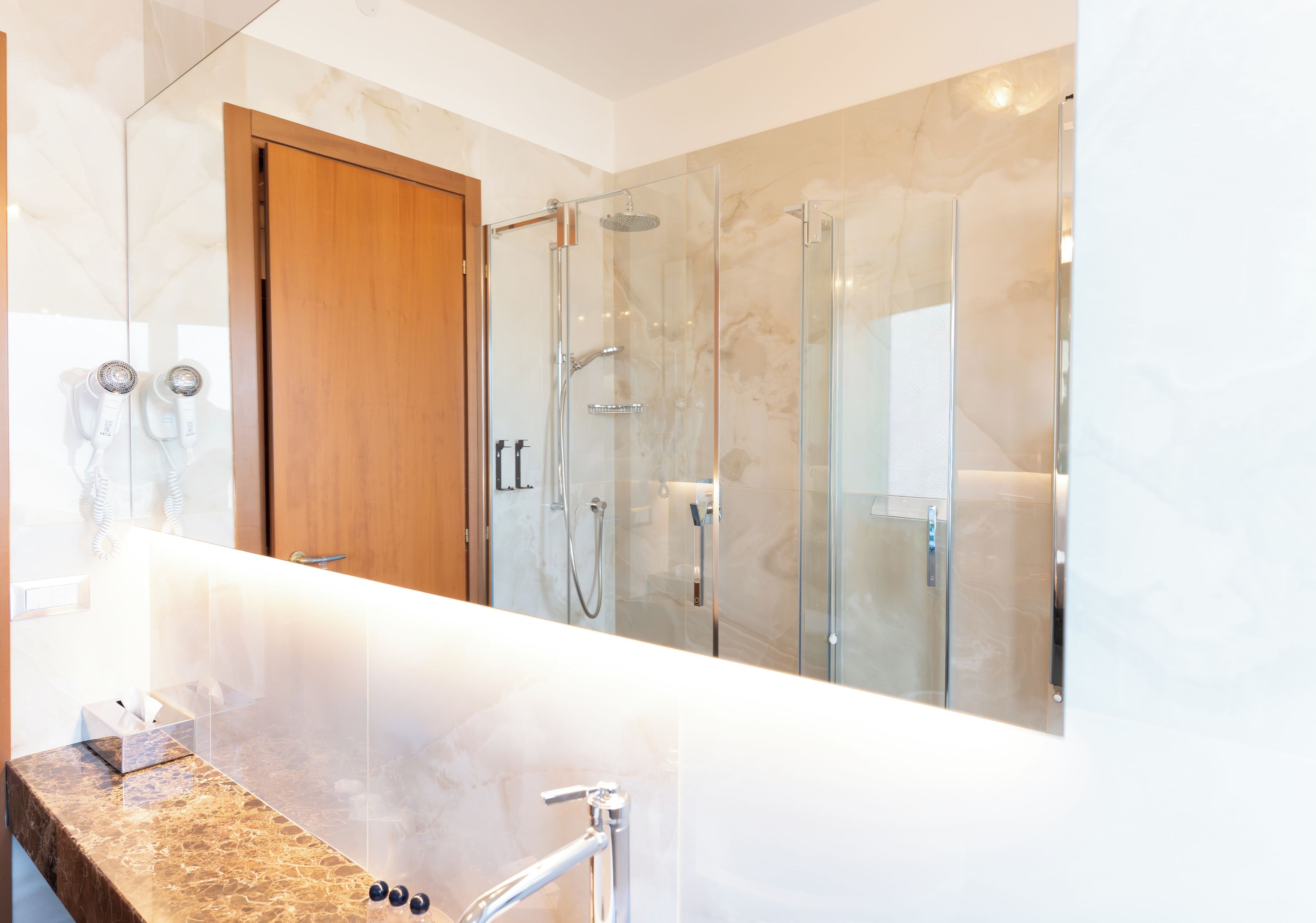 Une salle de bain moderne avec un meuble-lavabo en marbre, une cabine de douche en verre et une porte en bois.