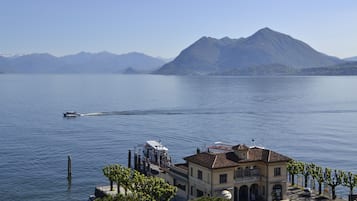 A lakeside building with a dock, boats, and mountains in the background.