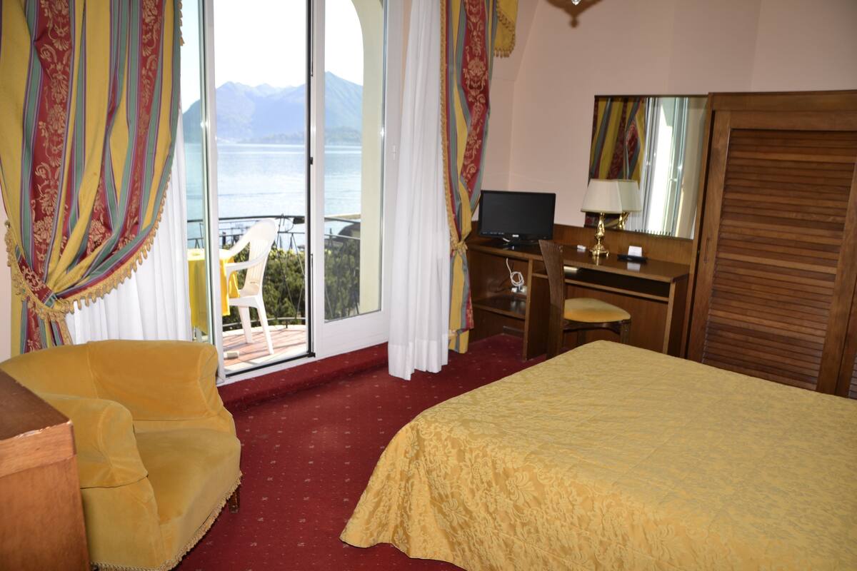 Une chambre d’hôtel avec un lit, un bureau, une chaise et une vue sur l’extérieur.