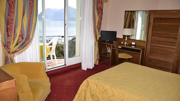 Habitación de hotel con cama, escritorio, silla y vistas al exterior.