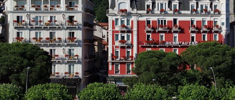 A hotel with multiple floors, balconies with flower boxes, and a prominent red facade.