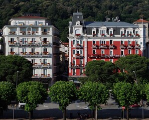 Un hotel amb diverses plantes, balcons amb jardineres i una façana vermella destacada.