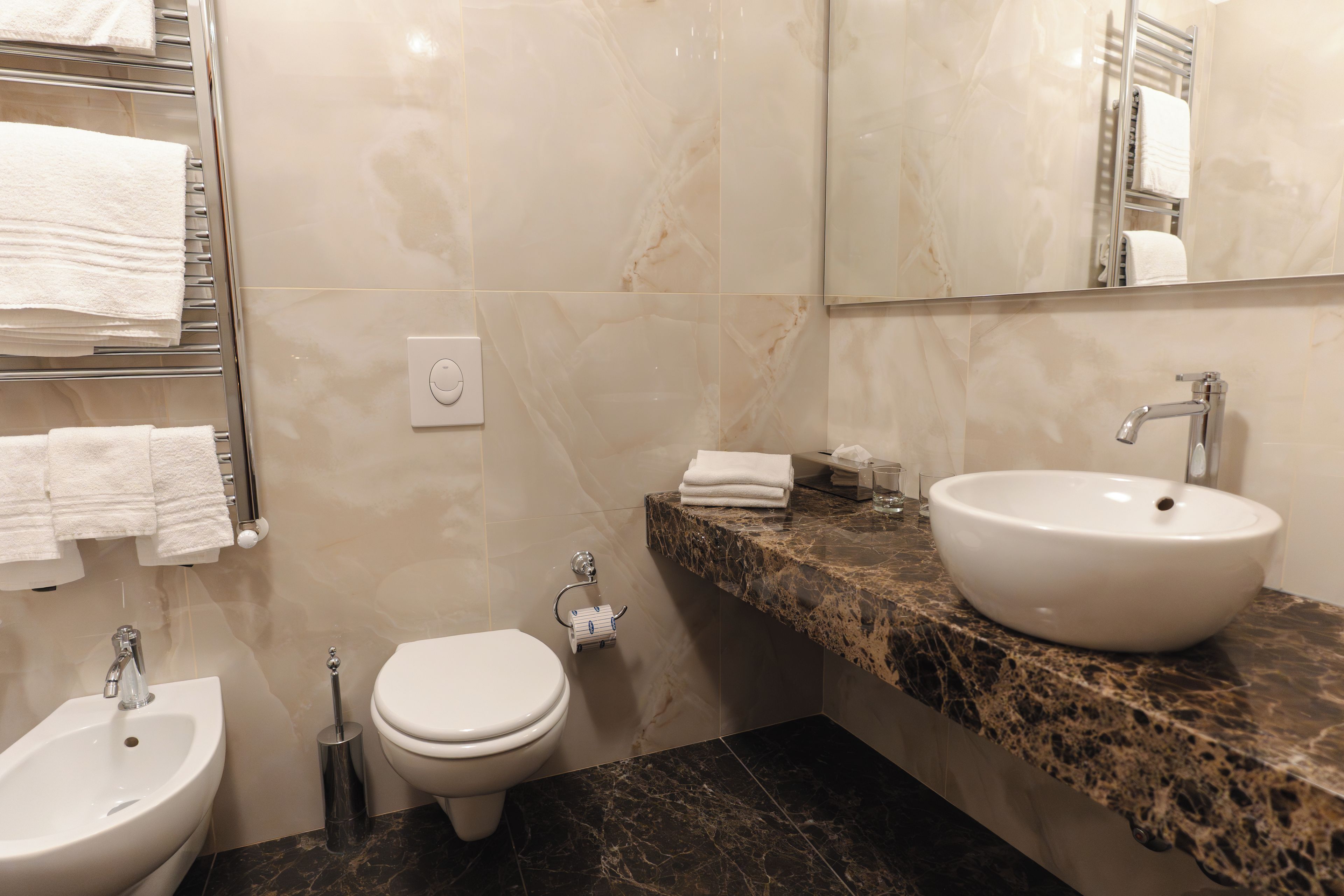 Un bagno con bidet, toilette, lavandino e portasciugamani.