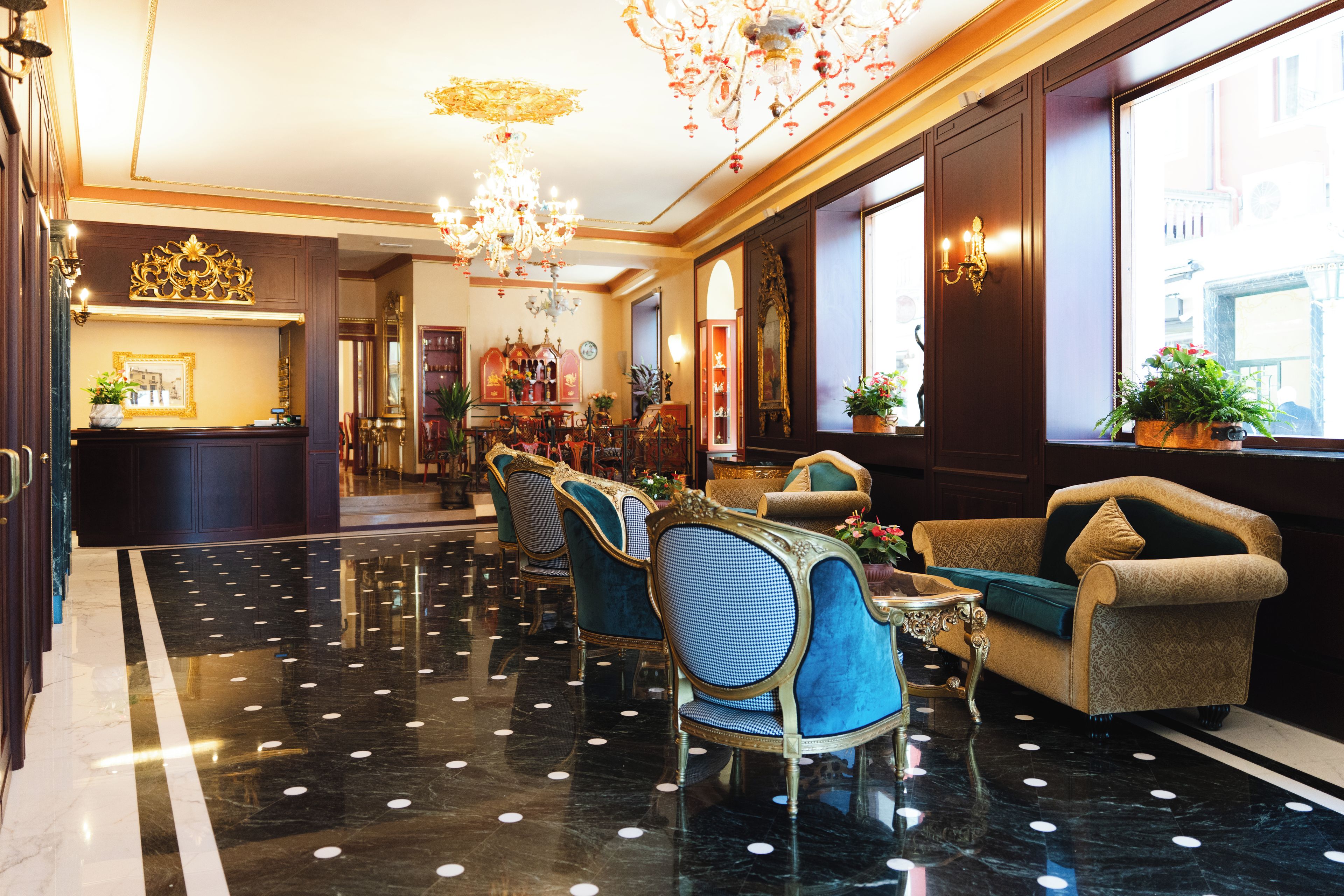 A hotel lobby with a chandelier, seating area, and a reception desk.