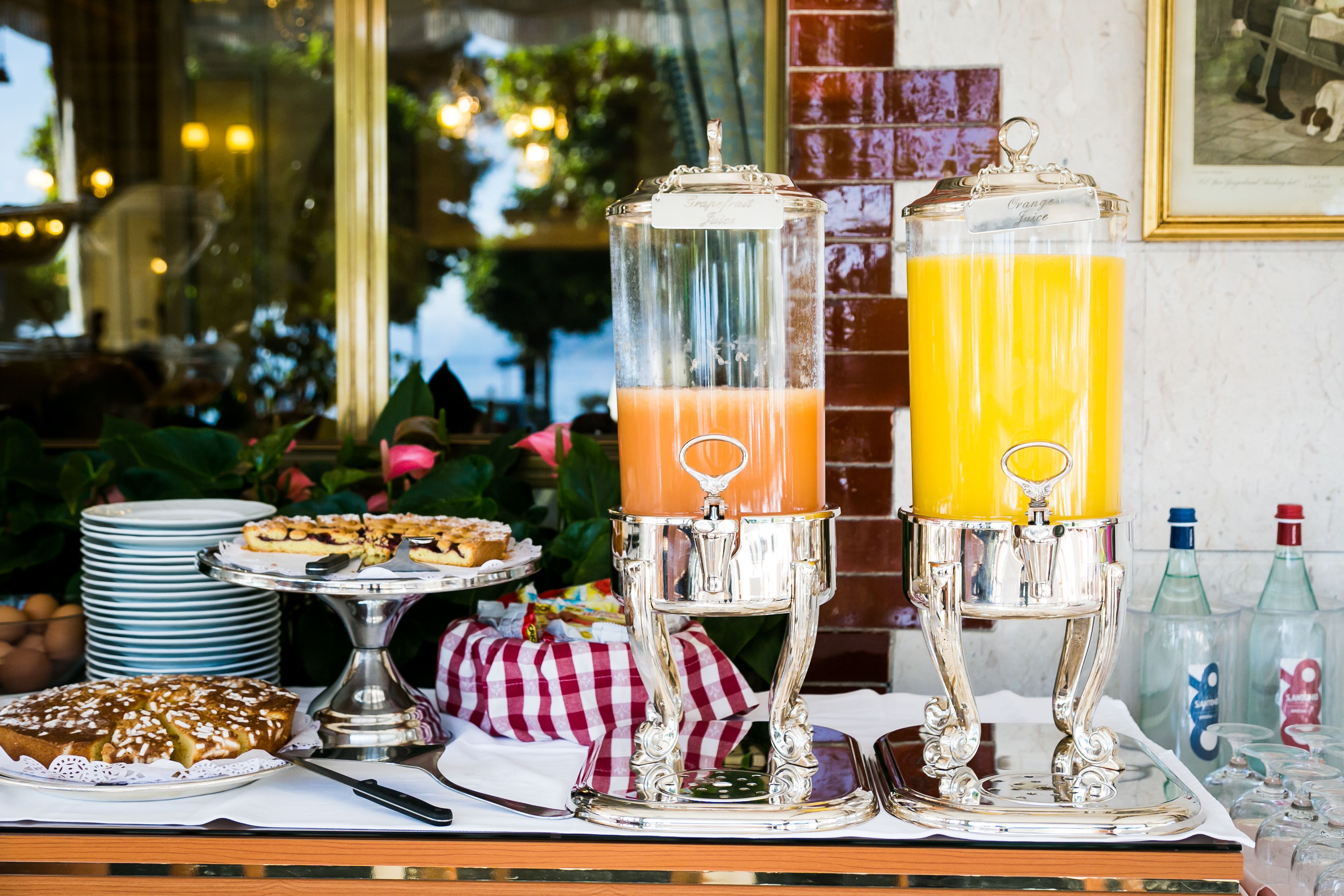 A breakfast buffet with a variety of foods and two juice dispensers.
