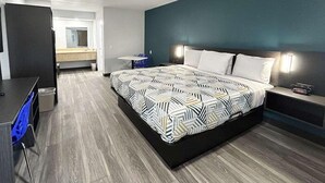 A modern hotel room with a large bed, a desk, a chair, and a small table. - Value Stay Inn Extended Stay Bakersfield (Bakersfield)