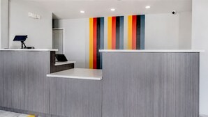 A reception desk with a modern design, a color-blocked wall, and a security camera. - Value Stay Inn Extended Stay Bakersfield (Bakersfield)