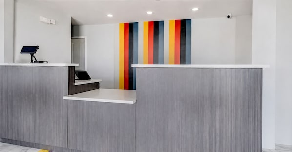A reception desk with a modern design, a color-blocked wall, and a security camera.