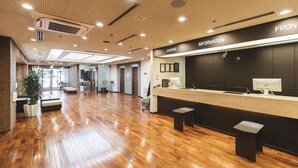 Un vestíbulo amplio con piso de madera, un mostrador de recepción con la etiqueta 'FRONT INFORMATION' y un letrero que dice 'CASHIER'.