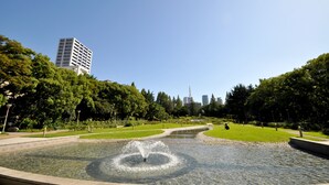 Un parque con una fuente, vegetación y un edificio a lo lejos.
