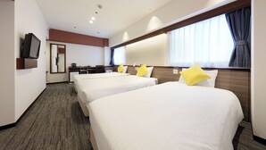 Habitación de hotel con tres camas individuales, un televisor en la pared, un escritorio con una silla y un amplio ventanal con cortinas.