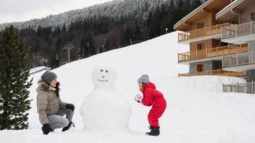 A snowman with two people in winter clothing.