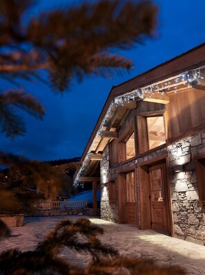 Una casa de madera con paredes de piedra, ventanas grandes y un porche.