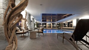 Área interna de piscina com espreguiçadeiras e uma parede de pedra.