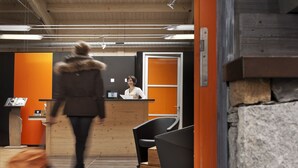 Un intérieur moderne avec un comptoir d’accueil, un fauteuil noir et un mur en pierre.